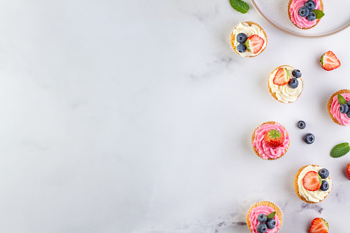 Background marble table with cupcakes and berries on the side, copy space