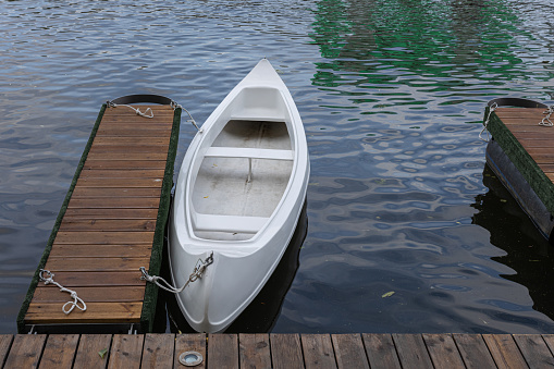 a plastic canoe is tied to a wooden pier. High quality photo
