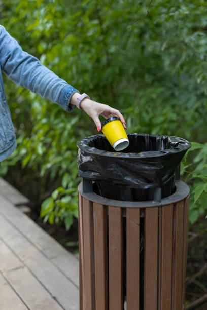 istock a woman's hand throws a paper cup into the trash 1404034276