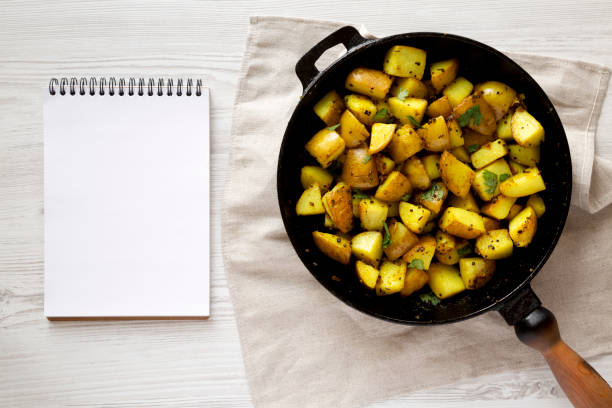 istock Homemade Roasted Potatoes with Mustard Seeds in a cast-iron pan, blank notepad, top view. Flat lay, overhead, from above. 1404034300