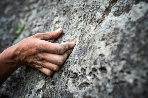 Close up shot of an adult male handholding on to a rock, illustration for rock climbing.