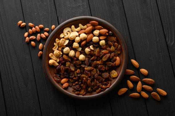Hazelnuts, cashews, raisins, almonds, peanuts, walnuts on a wooden black background stock photo