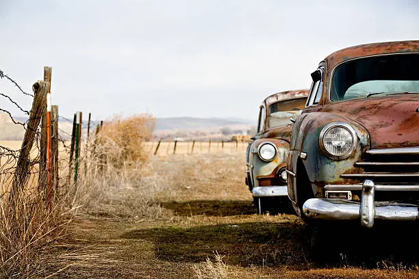Photo of Old cars abandoned in a fenced field