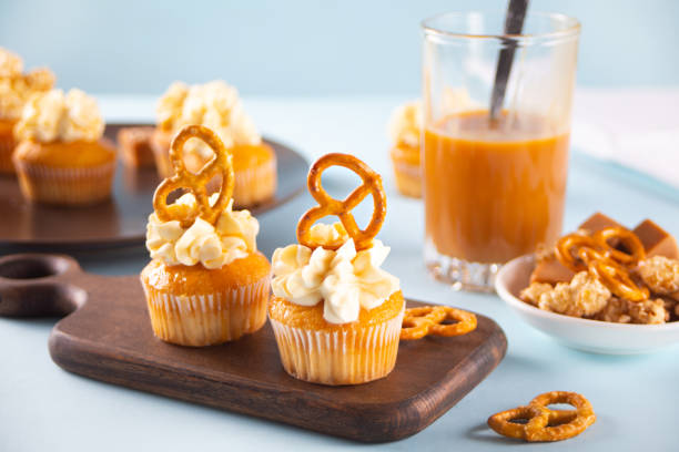 Homemade fresh cupcakes with sweet caramel syrup with whipped cream cheese and brezel waffles decoration Homemade cupcakes with sweet caramel syrup and whipped cream cheese with brezel waffles. CUPCAKE stock pictures, royalty-free photos & images