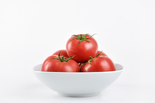 Front view tomatoes in the white bowl on the white background