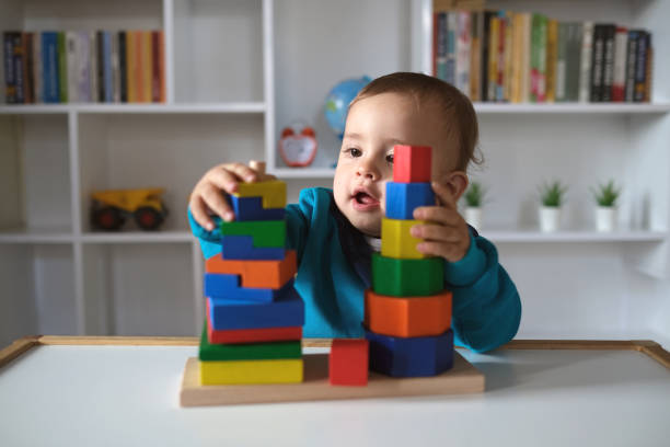 neuer junge, der mit mehrfarbigem holzblockspielzeug spielt - kleinstkind stock-fotos und bilder