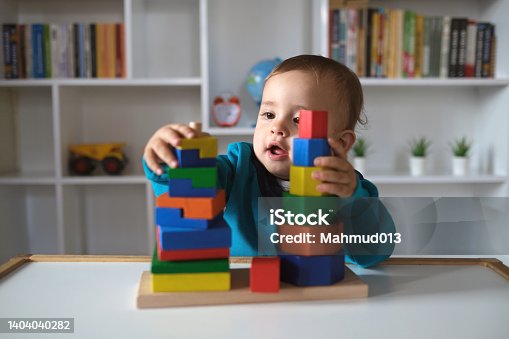 istock New boy playing with multi colored wooden block toys 1404040282
