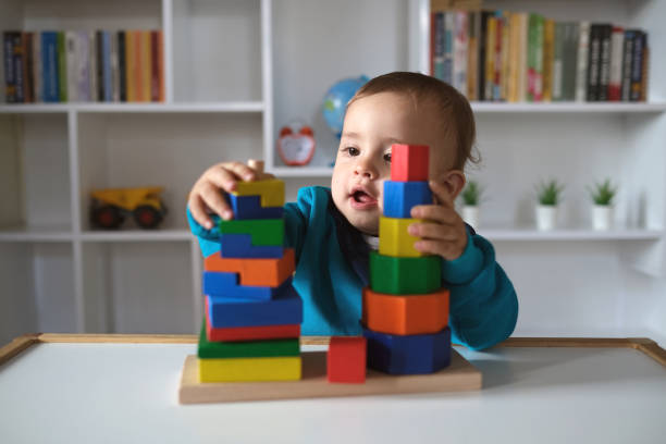 novo menino brincando com brinquedos multicoloridos bloco de madeira - criança pequena - fotografias e filmes do acervo