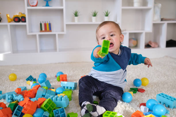 New boy playing with multi colored wooden block toys stock photo