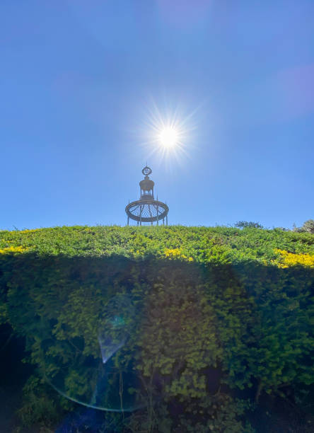 Horizontal landscape photo of a formal garden bed surrounded by pathways and distant people relaxing and walking, a pond and trees in the background on the horizon at the famous park in the old centre of Paris, the Jardin des Tuileries.