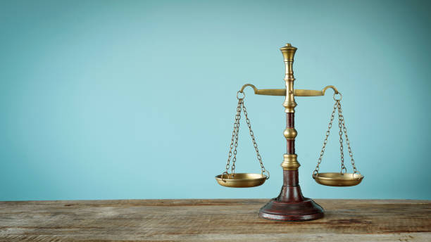 scales of justice on the wooden table - gerechtigheid fotos stockfoto's en -beelden