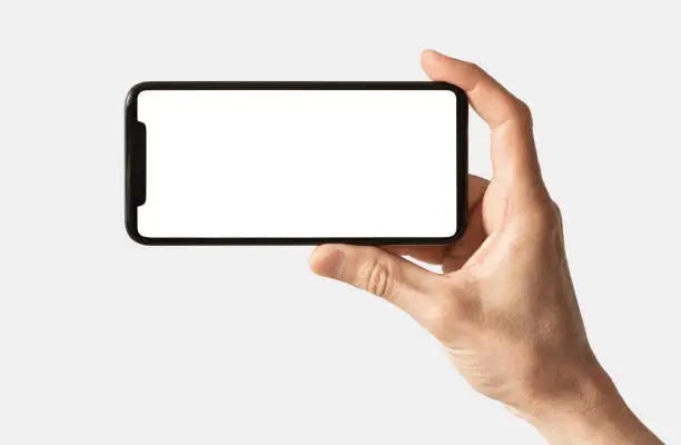 Photo of Male hand showing smartphone with white blank screen mock-up, isolated on grey background