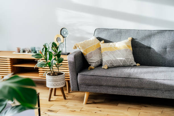 istock Stylish living room interior with designer console with decor and gray sofa with graphic pillows. White walls, green plants in the pots. Light wooden oak parquet. Modern Scandinavian style interior. 1404048111