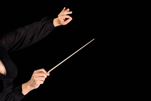 Female conductor conducting a symphony with her baton on a black background