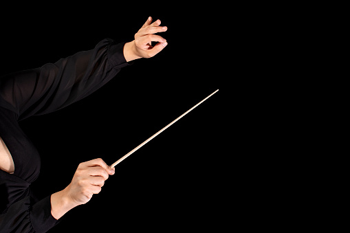Female conductor conducting a symphony with her baton on a black background