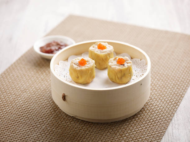 Steamed Pork Dumpling Siew Mai with chopsticks served in a dish isolated on mat side view on grey background stock photo
