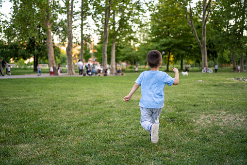 Back shot of little boy running in park