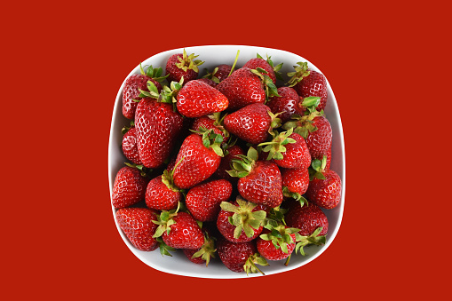 Strawberries in a bowl isolated on the red background with clipping path, bowl of strawberry