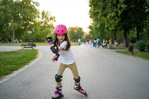 Cute little girl riding on roller skate in public park