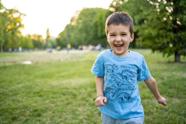 Happy little boy running in public park stock photo