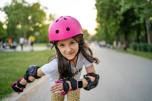 Caucasian girl riding in roller skates on road in park on summer day