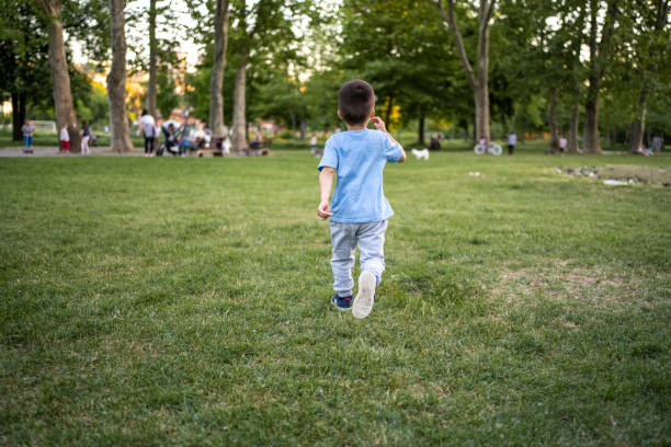 Back shot of little boy running in park