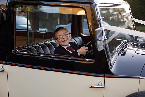 Very Young Driver A young boy poses as the driver of the wedding car before it takes the bride and groom to the reception. ring bearer stock pictures, royalty-free photos & images