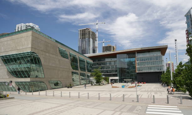 Surrey Civic Plaza, British Columbia, Canada Surrey, Canada - June 17, 2022: The Surrey Libraries - City Centre Branch stands to the left on Surrey Civic Plaza. Surrey City Hall to the right was designed by Moriyama & Teshima Architects of Toronto. Background shows residential buildings under construction in the downtown district. Spring midday with light clouds over Metro Vancouver. surrey british columbia stock pictures, royalty-free photos & images