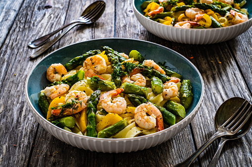 Noodles with fried prawns and asparagus on wooden table