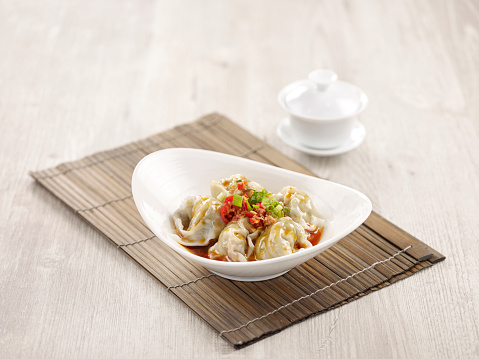 Pork Wanton in Chilli Vinaigrette with chopsticks served in a dish isolated on mat side view on grey background