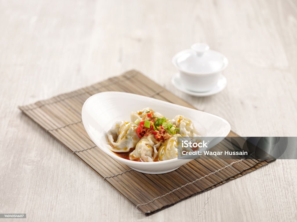 Pork Wanton in Chilli Vinaigrette with chopsticks served in a dish isolated on mat side view on grey background Beijing Stock Photo