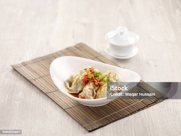 Pork Wanton In Chilli Vinaigrette With Chopsticks Served In A Dish Isolated On Mat Side View On Grey Background Stock Photo - Download Image Now