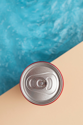 Refreshing drink in a tin can next to the pool. Top view.