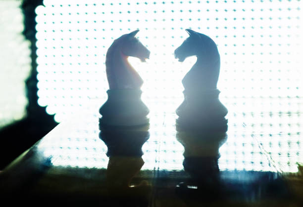 Pair of knights face off, lit from behind by a bright array of LEDs.