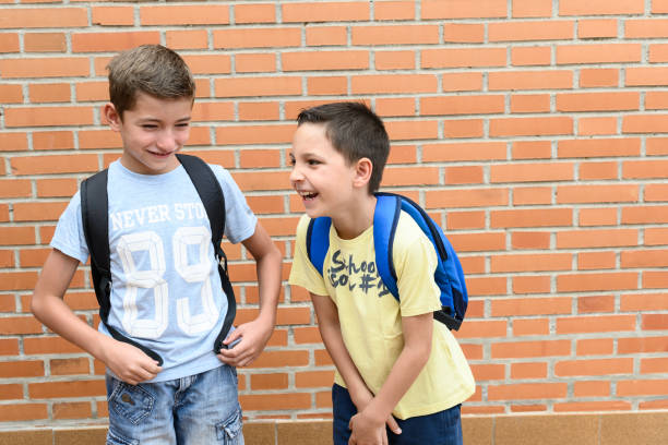 Two children laughing. Students carrying a backpack. Concept of Back to school