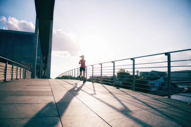 young sports woman running over bridge at sunset hour
