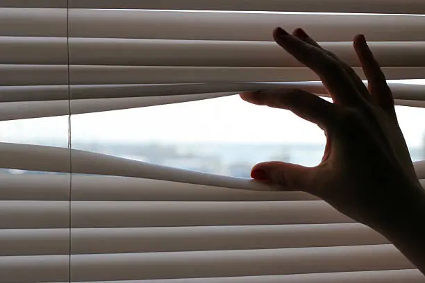 curious spy lady looking through roller-blind