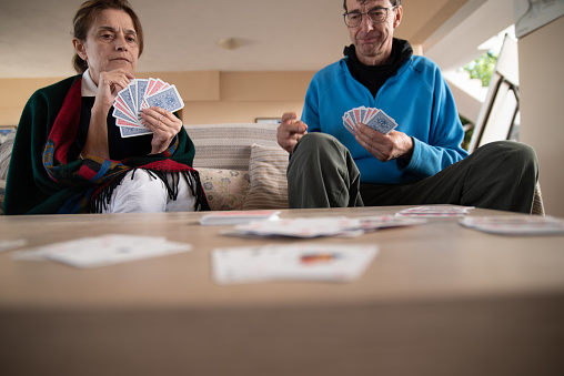 Mature Man and Mature Woman Playing Cards in Domestic Living Room