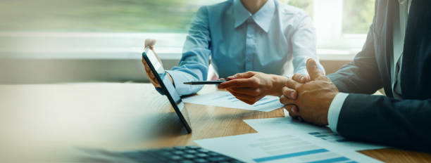 business consulting services. advisor and businessman working with digital tablet at desk in office. corporate strategy - financieel adviseur stockfoto's en -beelden