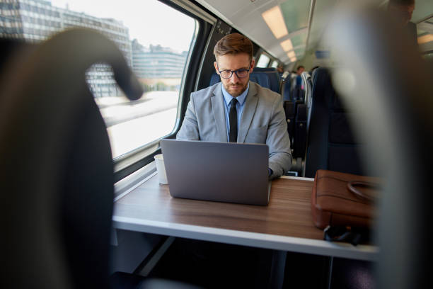 Businessman working on train using laptop stock photo