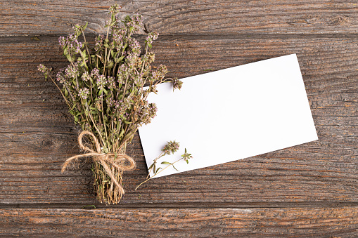 Dried thyme and paper card on wooden background