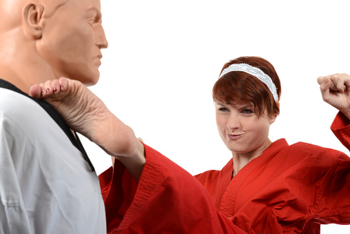 Martial artist kicking a training mannequin.