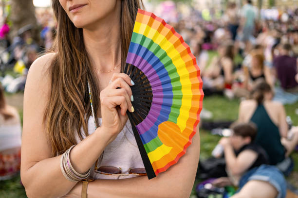 Woman holding rainbow hand fan.