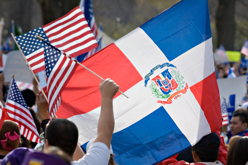 Big Dominican flag and small American flags side by side at immigration rally