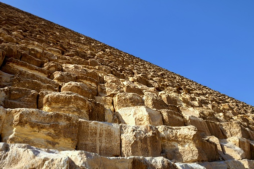 Giza, Egypt, April 15, 2022: Low angle view of the northern side of Pyramid of Cheops on the Giza Plateau on a spring morning. The pyramid field of Giza is listed as UNESCO World Heritage Site.