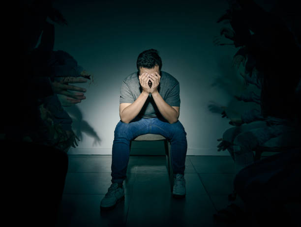 One mixed race male suffering mental illness in asylum. Caucasian schizophrenic man experiencing depression while being surrounded by people on a stage theatre performance One mixed race male suffering mental illness in asylum. Caucasian schizophrenic man experiencing a depression while being surrounded by people on a stage theatre performance schizophrenia photos stock pictures, royalty-free photos & images