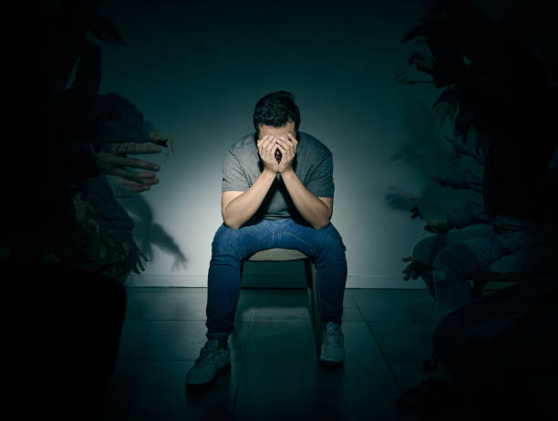 one mixed race male suffering mental illness in asylum. caucasian schizophrenic man experiencing depression while being surrounded by people on a stage theatre performance - hastalık belirtisi fotoğraflar stok fotoğraflar ve resimler