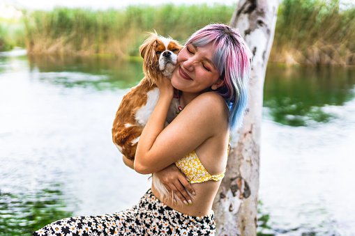 Portraits of young woman and her dog by the lake
