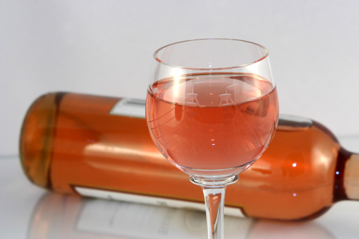 A refreshing glass of white zinfandel with the bottle in the background.