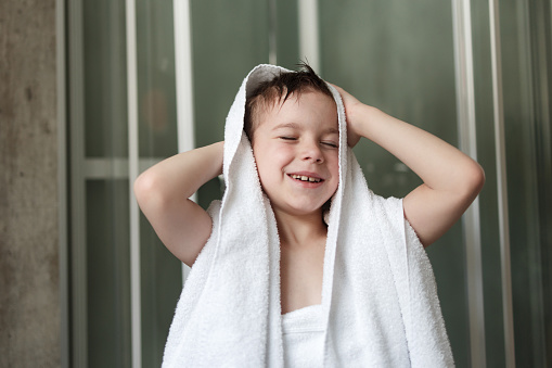 Happy boy drying himself with a towel after shower in the bathroom